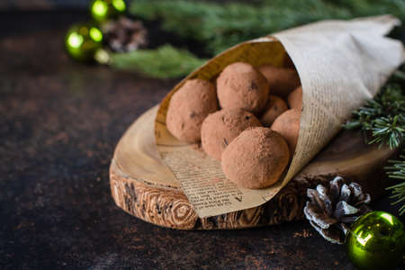 Homemade chocolate truffles on the paper on stone concrete table background with festive holiday decoration. Christmas Dessertの写真素材