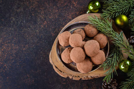 Homemade chocolate truffles on the paper on stone concrete table background with festive holiday decoration. Christmas Dessertの写真素材