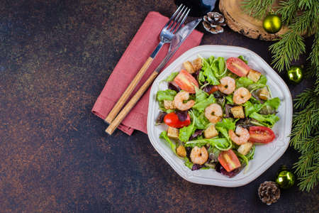 Fresh caesar salad with shrimps on white plate dark stone table background with Christmas Festive Decoration. Healhty Food Snack Concept. Top view Copy Spaceの写真素材