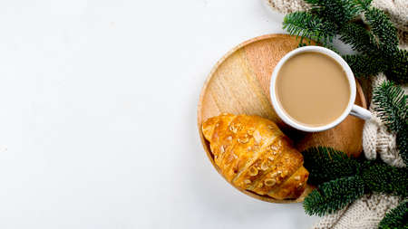 Christmas breakfast. Cup of coffee, croissant and holiday decoration toys, tree fir branches on white table. background. Top view, flat lay. Banner imageの写真素材