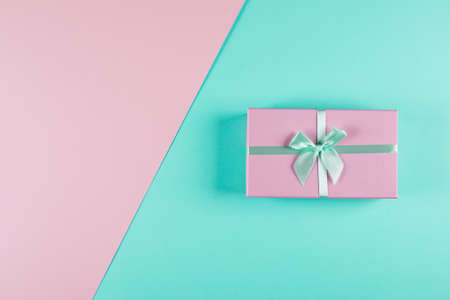 Pink gift box on a mint pink background. Two-color background. Holiday christmas birthday concept. Top view, flat lay, copy spaceの写真素材