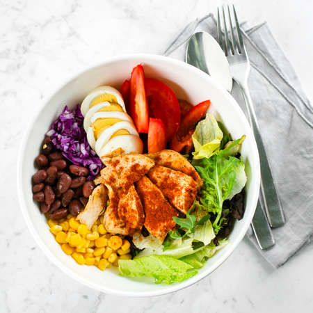 Top view of lunch bowl with chicken, egg, tomatoes, lettuce, corn, red beans, red cabbage. Clean food and dieting nutrition concept. Copy space, flat layの写真素材