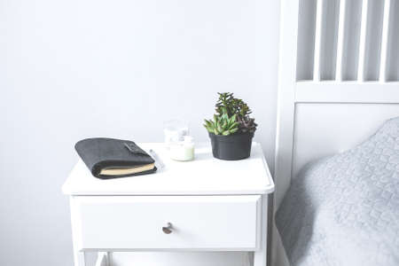 Tiny succulents, candles and black notebook on bedside table in the bedroom in scandinavian style...