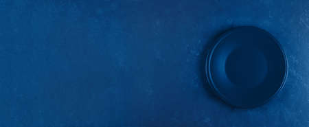 Empty plate on blue concrete background. Classic blue. Trend color of 2020 year. Top view with copy...