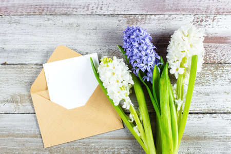 Mother's day Holiday Concept. Hyacinth, flowers and empty card on shabby wooden background. Greeting card for Womens or Mothers Day. Flat lay, top view, copy space. Mockup concept.の写真素材