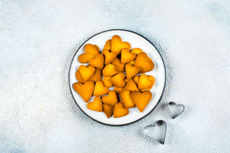 Plate with sweet cookies for Valentines day. Shortbread cookies in shape of heart and cookies cutters on concrete table background. Top view, flat lay, copy spaceの写真素材