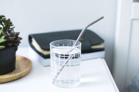 Eco natural metallic straws in glass with water on bedside table. ustainable lifestyle concept. zero waste, plastic free.の写真素材