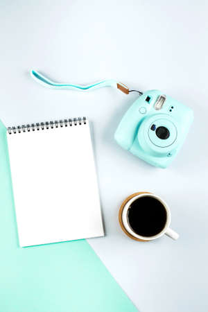 Flat lay with modern mini camera, empty notebook and cup of coffee on double grey green background. Top view, flat lay style composition. Fashion blogger, minimal conceptの写真素材