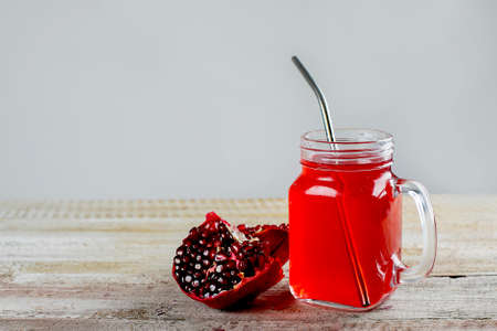 Mason jar with healthy pomegranate juice and fresh pomegranate on the wooden background. Zero waste...