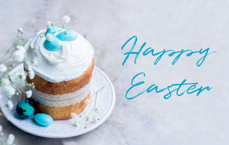 Happy Easter card. Traditional Easter cake kulich decorated meringue and blue candy cane shape eggs on plate on gray stone table background.の写真素材
