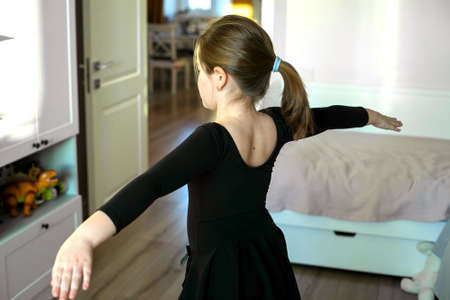 Schoolgirl doing sports exercises - gymnastics, choreography. Stay at home. Concept of self isolation, quarantine, online education.の写真素材