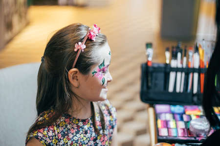 Girl draws little girl aqua makeup. Face painting. Children leisure