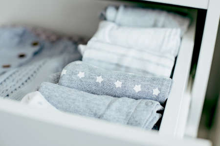 Baby or newborn things of white, blue and grey colors are in the drawer. Lady fly system, kondo, konmary concept. Home lifestyle.の写真素材