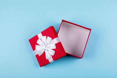 Open red gift box on blue paper background. Top view, flat lay, place for object. Mockup, holiday concept.の写真素材