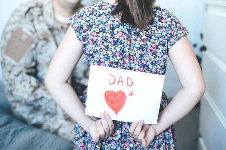 Happy fathers day. Child daughter congratulates dad and gives him postcard. Family holiday and togetherness.の写真素材