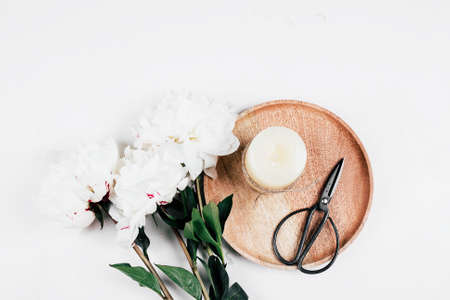 White peony and wooden tray with candle, scissors on white background. Cozy, still life, minimal concept. Top view, flat lay, copy spaceの写真素材