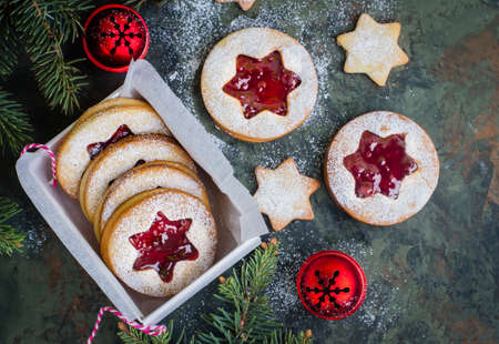 Christmas cookies. Linzer cookies with raspberry jam on green table background. Traditional Austrian biscuits filled. Top view and copy spaceの写真素材