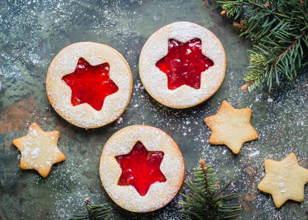 Christmas cookies. Linzer cookies with raspberry jam on green table background. Traditional Austrian biscuits filled. Top view and copy spaceの写真素材