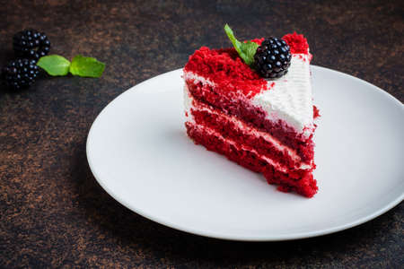 Red velvet cake on a white plate on dark stone table background. Copy space