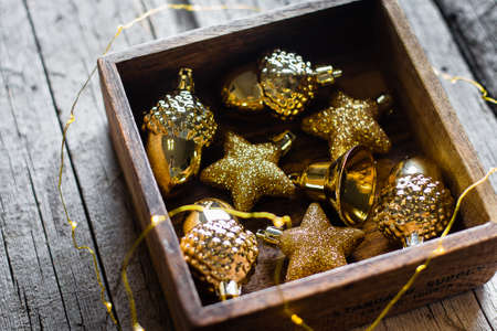 Gold decorative Christmas toys in wooden box on wooden table backgroundの写真素材