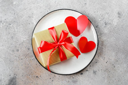 Valentine's Day Table Setting. Plate with Gift box and two red hearts. Flat lay, top viewの写真素材