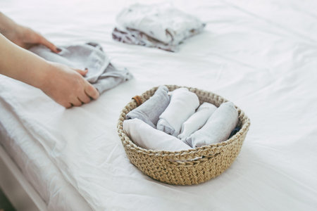 Woman folding clothes in jute basket in the konmari system. Concept of organizing minimalism clothes.の写真素材