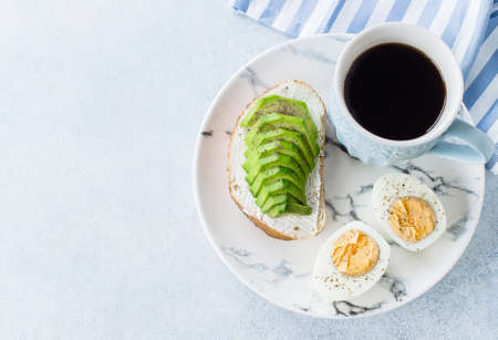 White desktop table with laptop, fresh toast with avocado, mug of coffee and Havortia. Woman...