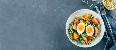 Healthy vegan salad of fresh tomato, arugula, salmon, egg and sesame on plate. Diet menu. Top viewの写真素材