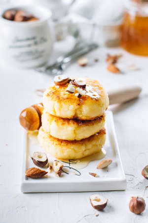 Breakfast or lunch concept. Cottage cheese pancakes with honey, nuts and mint on white background....