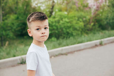 Portrait of fashionable cute boy in white T-shirt outdoor in park. Concept of style and fashion for...
