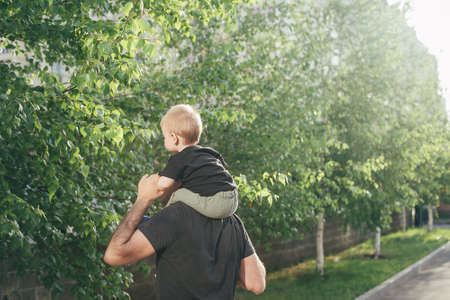 Father and Son walking together. Baby taking first steps with father help. Authentic moment, summer lifestyleの写真素材
