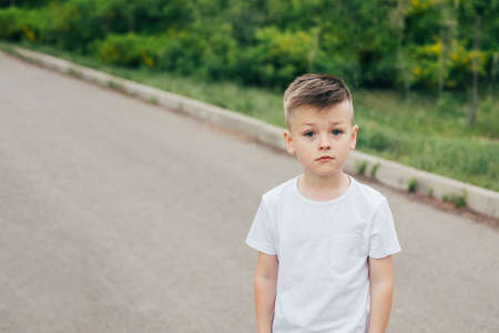 Portrait of fashionable cute boy in white T-shirt outdoor in park. Concept of style and fashion for...