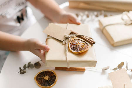 Holiday preparation and gift wrapping with craft paper on white table. Gift wrapped in brown paper and tied with rough twine and label for text. Top viewの写真素材