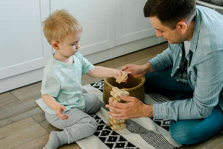 Happy little boy and man splash water on a home flower. Father dad and toddler son having fun. Plant...