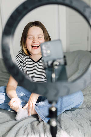 Caucasian teen girl speaking in front of camera for vlog. Teenager working as blogger, recording video tutorial for blog at home. Young Blogger Concept.の写真素材