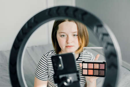 Caucasian teen girl speaking in front of camera for vlog. Teenager working as blogger, recording video tutorial for blog at home. Young Blogger Concept.の写真素材