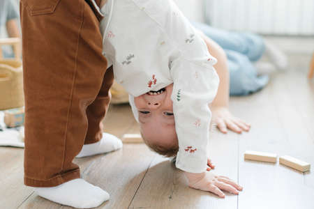 Children play on the floor of the children's room. Little brother amuses his brother and sister...