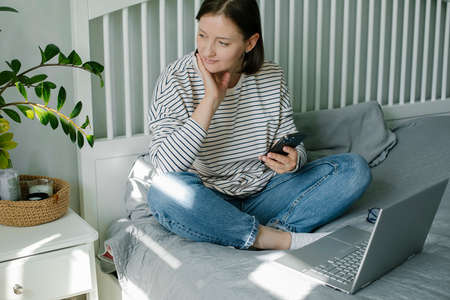 Young woman working from home office. Freelancer using laptop, phone and the Internetの写真素材