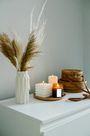 Home interior decor in beige neutral colors. White dresser with dried flowers in vase, rattan bags and candle. mockup conceptの写真素材