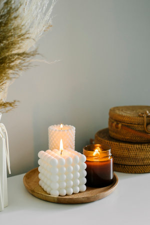 Cozy burning candles on white shelf. Concept of winter or autumn home decorの写真素材