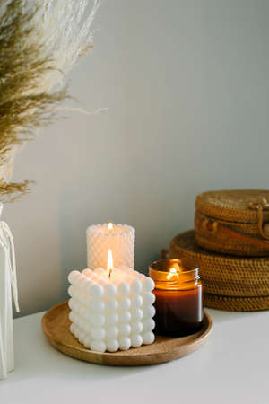 Cozy burning candles on white shelf. Concept of winter or autumn home decorの写真素材