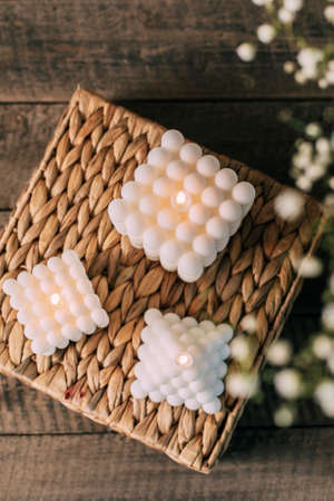 Home interior floral decor. Three trendy soy cube bubble candle on wooden table. top view, flat layの写真素材