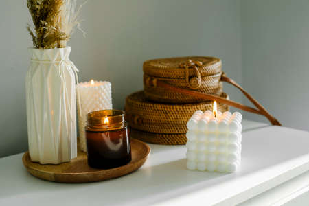 Elegant home decoration with wooden wick burning candle in brown glass jar and babble candles.の写真素材