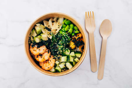 Shrimp poke bowls with seaweed, avocado, mango, cucumber, rice, pickled ginger, sesame seeds. Top...