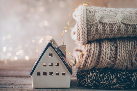 Ceramic house insulated by warm sweater. Concept of protection of house and lack of heat at home in winter. selective focusの写真素材