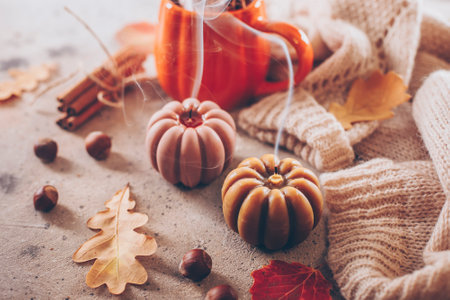 Extinguished candle with smoke, mug with autumn drink, leaves, warm sweater and cinnamon. Halloween holiday conceptの写真素材
