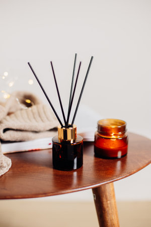 Home aroma fragrance diffuser and burning candles on wooden table in the bedroom. Interior elements. Copy spaceの写真素材
