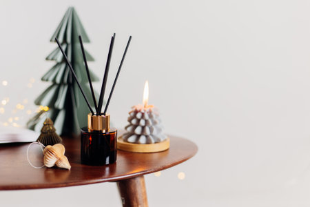 Home aroma fragrance diffuser and burning candles shape of tree on wooden table in the bedroom. Interior elements. Christmas and Winter decorationの写真素材