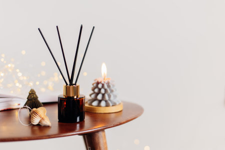 Home aroma fragrance diffuser and burning candles on wooden table in the bedroom. Interior elements. Christmas and Winter decorationの写真素材