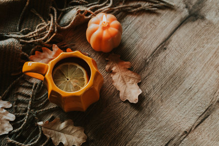 Warm autumn ambiance featuring a pumpkin-shaped mug with tea and a lemon slice, surrounded by...